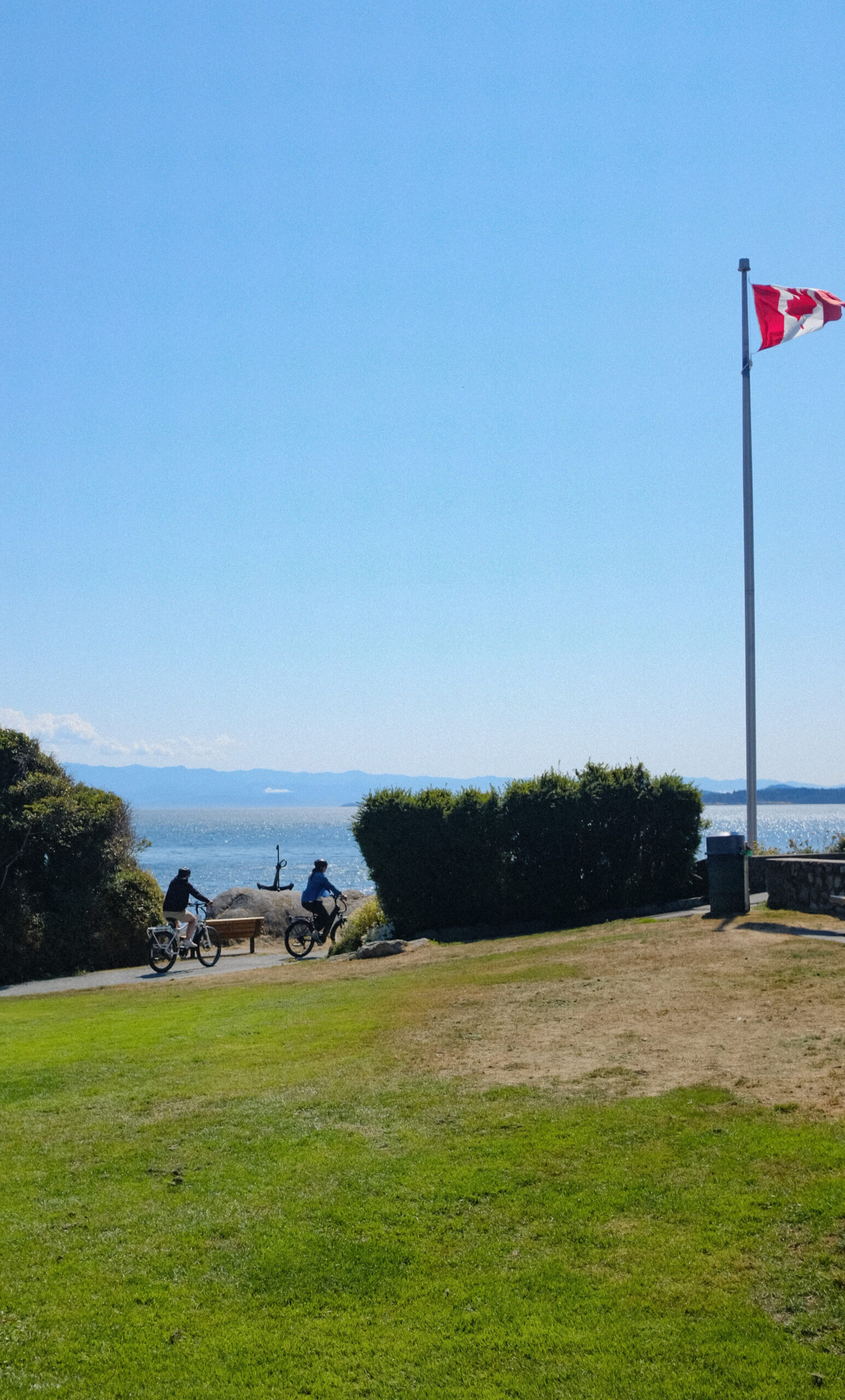 Two riders on e-bikes with ocean view backdrop at Saxe Point Esquimalt